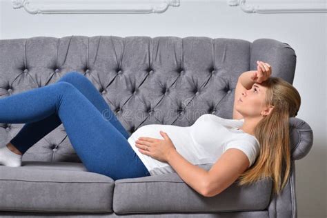 Pregnant Woman Feels Abdominal Pain And Lies On The Sofa Stock Photo