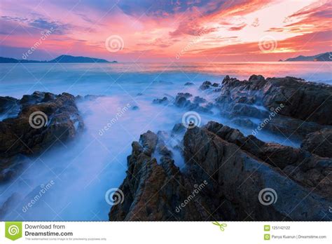 Long Exposure Image Of Dramatic Sky And Wave Seascape With Rock Stock