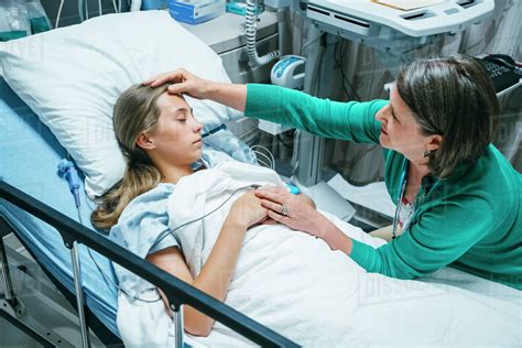 Caucasian Doctor Comforting Patient In Hospital Bed Stock Photo