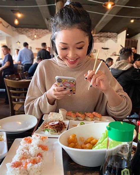 A Woman Sitting At A Table With Food And Chopsticks In Front Of Her