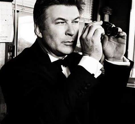A Black And White Photo Of A Man In A Tuxedo Holding A Camera