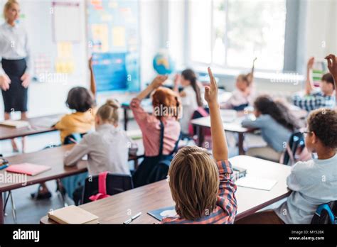 Pupils Raising Hands On Lesson To Answer Teacher Question Stock Photo