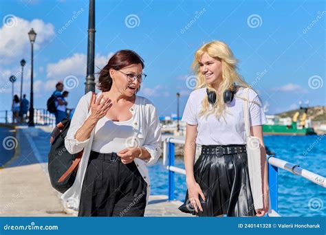 Mom And Teenage Daughter Walking Talking Together In Summer City Stock