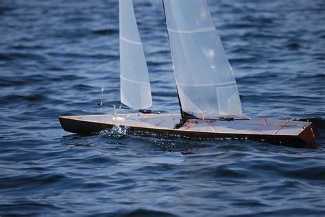 A Small Sailboat With White Sails In The Water