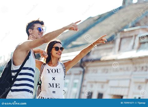 Two Young Tourists Sightseeing A Town Pointing With Finger Stock Image