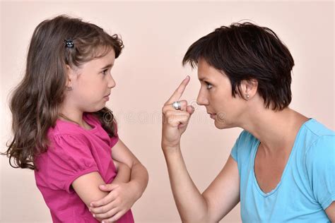 Angry Mother And Scared Daughter With Smartphone Looking At Each Other