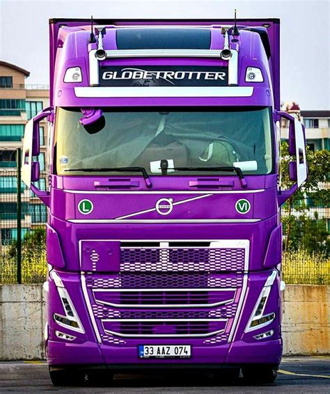 A Purple Semi Truck Parked In Front Of A Building On The Side Of The Road