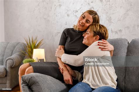 Photo Libre De Droit De Jeune Femme Sasseyant Sur Le Sofa Avec Sa Mère Qui La Câline Banque D