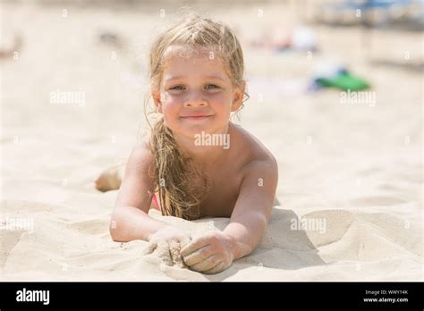 Pretty Girls Four Years Lying In The Sand On His Stomach On The Beach On A Sunny Day Stock Photo
