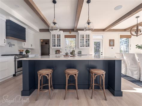 A pair of woven dome pendants, palecek green oaks pendant, hang over a navy kitchen island fitted with a prep sink and gold gooseneck faucet. 2019 QEII Lottery Dream Home (With images) | Lake house ...