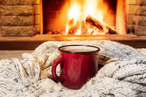 Cozy Scene Near Fireplace With A Red Enameled Mug With Hot Tea And Cozy