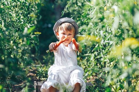 Premium Photo Baby Farmer With Carrots And Cacual Clother Sitting In