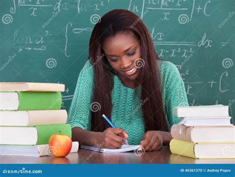 Female Teacher Writing In Book At Desk Stock Photo Image Of Girl