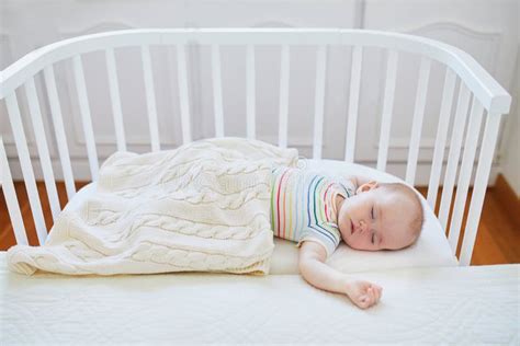 Baby Sleeping In Co Sleeper Crib Attached To Parents ` Bed Stock Image