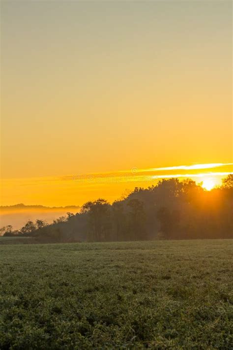 Colorful Sunrise With Misty Field And Hills In Background Stock Image