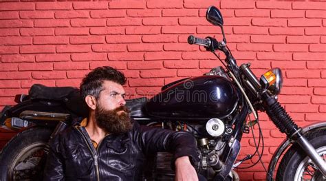 Man With Beard Biker In Leather Jacket Near Motor Bike In Garage