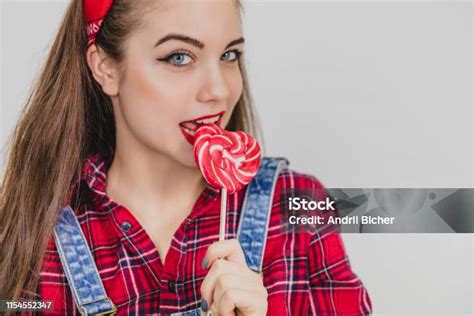 Pretty Pinup Girl Standing Licking Red Heartshape Lollypop Enticingly Pleased Face Expression