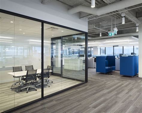 An Office With Glass Walls And Blue Chairs
