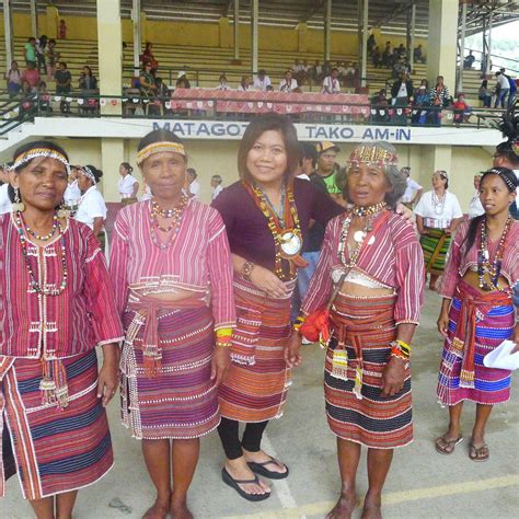 three women in colorful dresses standing next to each other with people watching from the stands