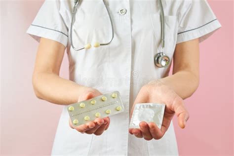 Female Doctor Holding Condom For Aids Prevention And Birth Control Pills Contraceptives In