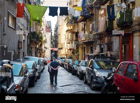 Couple Walking Down A Messy Street In Old City Of Naples Stock Photo