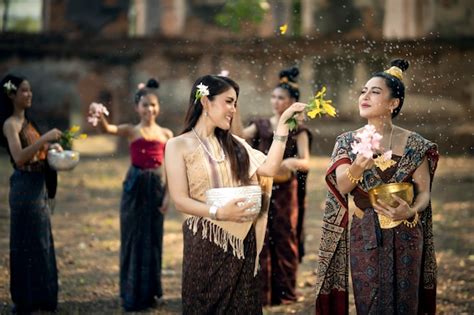 premium photo songkran festival a woman in thai national costume is splashing water on