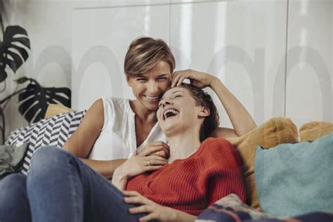 Happy Lesbian Couple Laughing And Cuddling On Couch Model Released