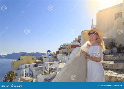 Blonde Woman Looking At Cityscape Of Oia Village In Santorini Island