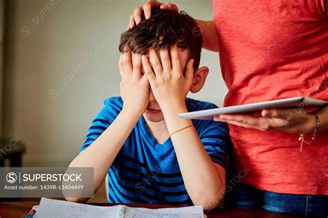 Mother Comforting Upset Son Doing Homework Superstock