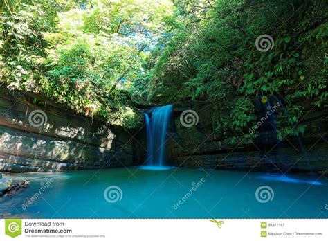A Cool Refreshing Waterfall Pouring Into An Emerald Pond Hidden In A