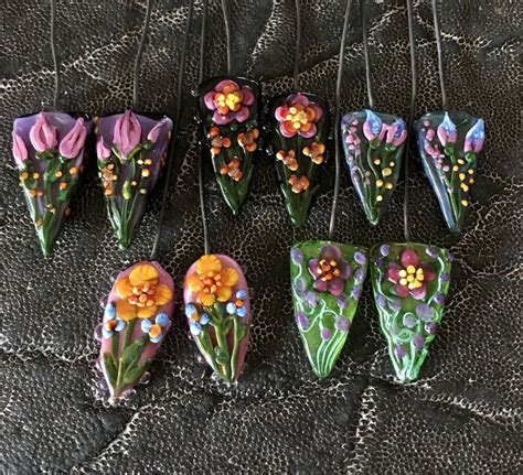 Six Pieces Of Art Glass With Flowers Painted On Them Sitting On A Lace