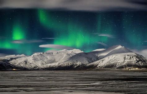 The Northern Lights Appear Over Snow Covered Mountains In