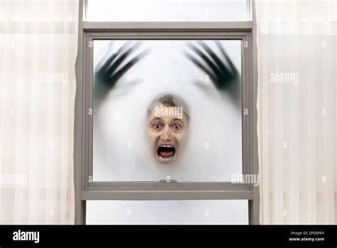 Screaming Man With Blurred Hands Has His Face Pressed Against The Window On A Foggy Background