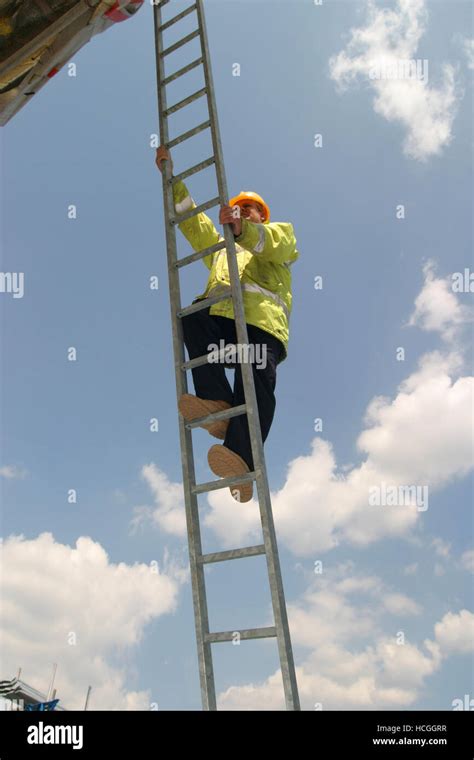 A Construction Worker Climbs A Long Steel Ladder Photographed From