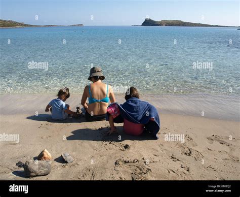 Mère et ses deux filles s assied sur une pittoresque plage de sable avec une vue sur l île de l
