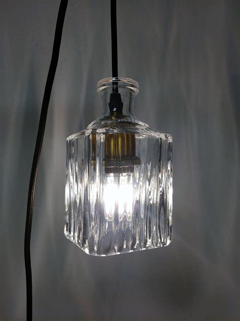 A Clear Glass Light Fixture Hanging From A Black Cord