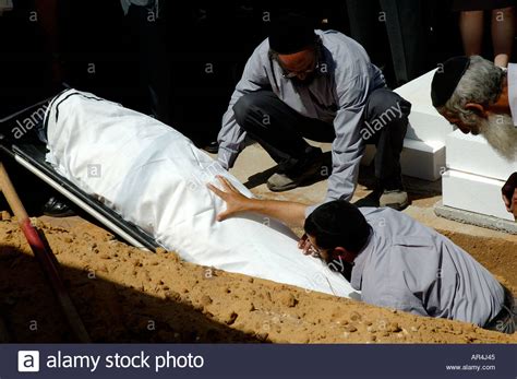 Orthodox Pallbearers Lower A Body Into A Grave At A Jewish