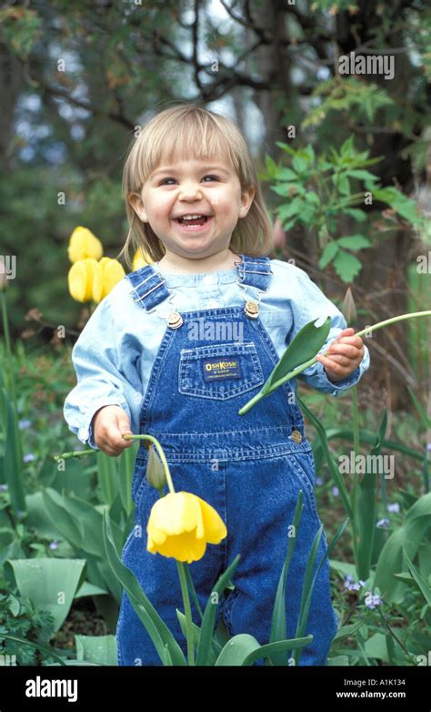 One Year Old Girl Standing In Garden Holding Tulips Stock Photo Alamy