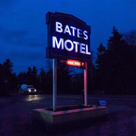 A Motel Sign Lit Up At Night With The Word Bates Motel On Its Side