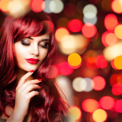 화려한 파티 보케 반짝이 배경에 긴 붉은 물결 모양의 머리를 가진 매력적인 빨간 머리 여자 프리미엄 사진