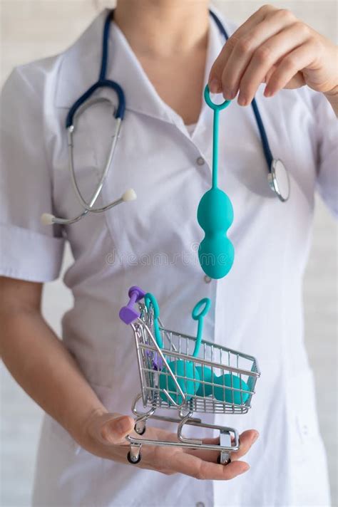 a faceless gynecologist puts a set of vaginal balls into a miniature shopping cart the doctor