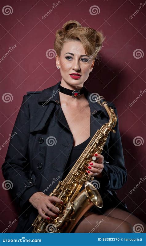 femme attirante sexy avec le saxophone posant sur le fond rouge jeune saxo jouant blond sensuel