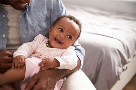 Close Up Of Father Holding Baby Daughter In Nursery Stock Photo