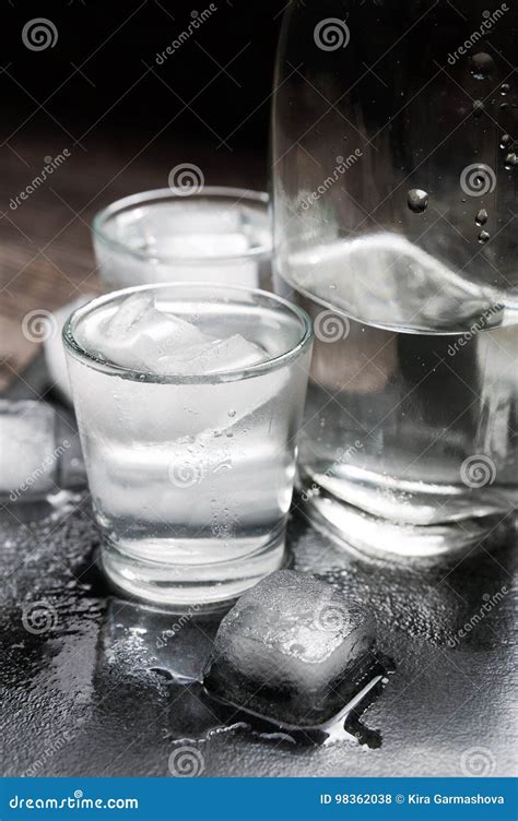Close Up View Of Bottle Vodka With Glasses Standing On Ice Black Stock