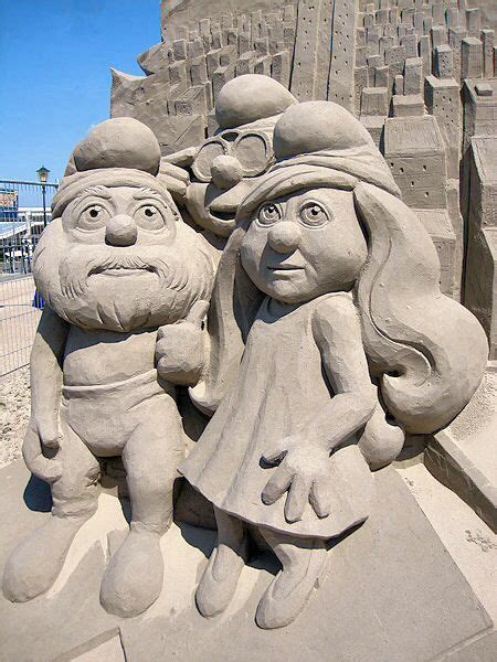Sand Sculpture Of Three People In Front Of A Castle