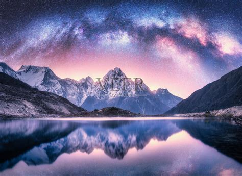 银河在雪山和湖的夜晚。景观上有白雪覆盖的高高的岩石，紫色的星空，倒影在尼泊尔的水中。天空的星星。喜马拉雅明亮的银河。空间。自然照片摄影图片