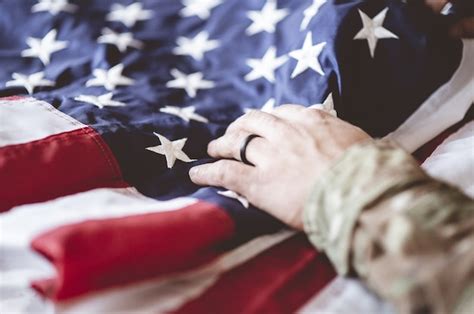 アメリカの兵士が彼の前にアメリカの国旗を悼んで祈っています 無料の写真