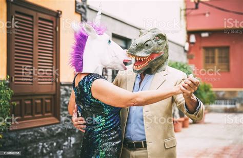 Crazy Couple Dancing And Wearing Dinosaur Trex And Unicorn Mask Senior
