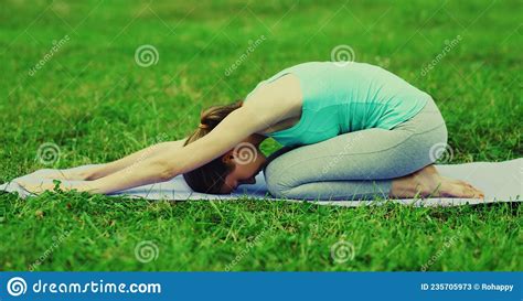 Fitness Woman Doing Yoga Exercises Back Stretching On Mat On The Grass