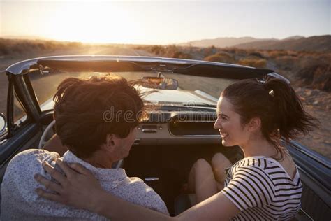 Rear View Of Couple On Road Trip Driving Classic Convertible Car